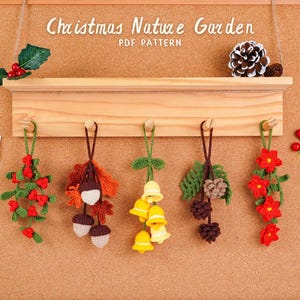 May include: A wooden shelf displaying five handmade crochet Christmas decorations. The ornaments include red berries, acorns, yellow bells, pinecones, and red flowers. The words "Christmas Nature Garden" are above the shelf.