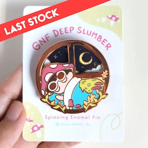 Peut inclure: Épingle en émail or rose représentant un personnage champignon dans une scène de fenêtre avec un fond de ciel nocturne. L'épingle porte le texte "GNF DEEP SLUMBER" et "Spinning Enamel Pin". La carte indique "LAST STOCK".