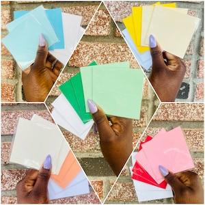 Puede incluir: Surtido de notas adhesivas cuadradas de colores en varios colores, incluyendo verde, azul, rosa y blanco. Las notas están dispuestas en pilas y se sostienen con las manos.