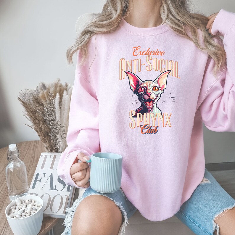 May include: Pink sweatshirt with a graphic of a hairless cat with the text "Exclusive Anti-Social Sphinx Club".