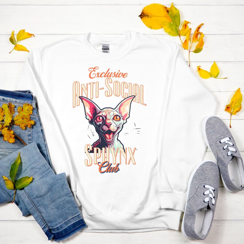 May include: White sweatshirt with a graphic of a Sphynx cat with the text "Exclusive Anti-Social Sphynx Club" in orange and yellow.