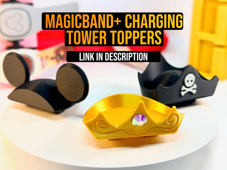 Pode incluir: Tr&ecirc;s toppers impressos em 3D para o carregador MagicBand. Os toppers t&ecirc;m a forma de orelhas do Mickey Mouse, um chap&eacute;u de pirata com uma caveira e ossos cruzados, e uma coroa dourada com uma joia.