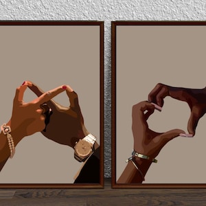 May include: Two framed prints with a brown background. Each print features a pair of hands forming a heart shape. One print shows the hands with gold bracelets and a watch, while the other print shows the hands with a watch and a bracelet.