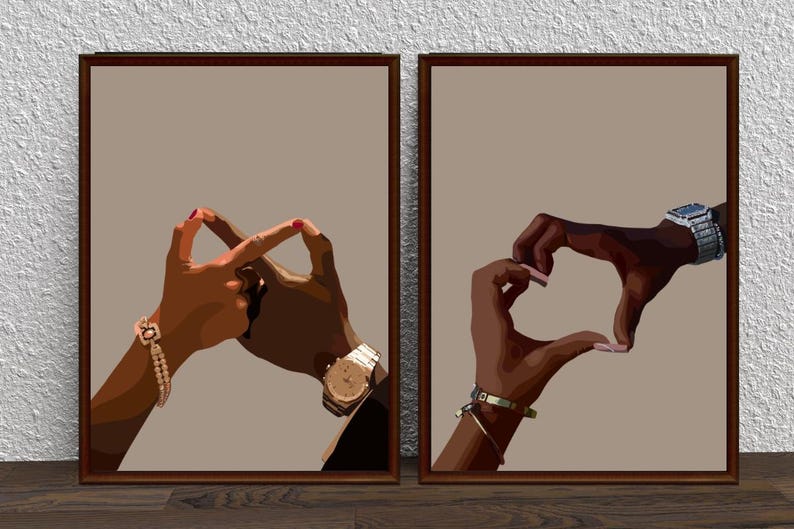 May include: Two framed prints with a brown background. Each print features a pair of hands forming a heart shape. One print shows the hands with gold bracelets and a watch, while the other print shows the hands with a watch and a bracelet.