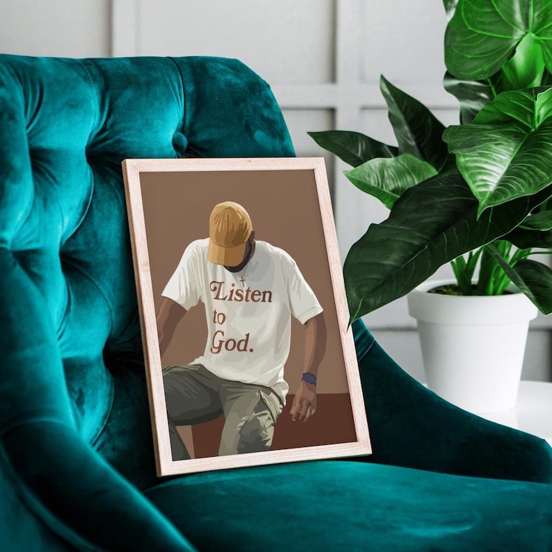 May include: A framed illustration of a person wearing a brown baseball cap and a white t-shirt with the text "Listen to God." The person is sitting on a brown surface.