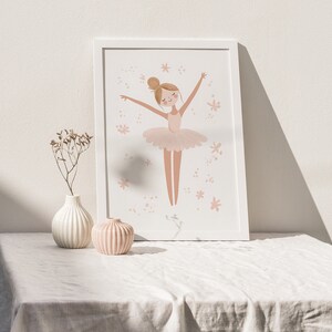 May include: A framed print of a ballerina in a pink tutu with her arms outstretched. The ballerina is surrounded by pink flowers. The print is in a white frame and is hanging on a white wall.