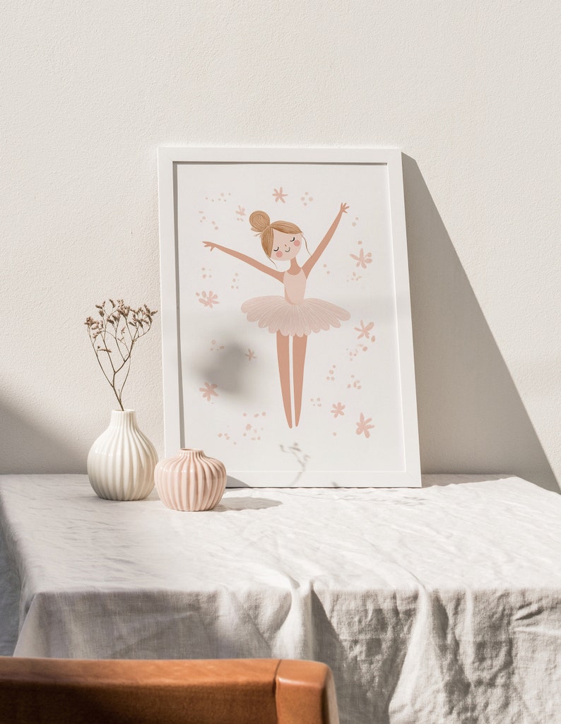 May include: A framed print of a ballerina in a pink tutu with her arms outstretched. The ballerina is surrounded by pink flowers. The print is in a white frame and is hanging on a white wall.