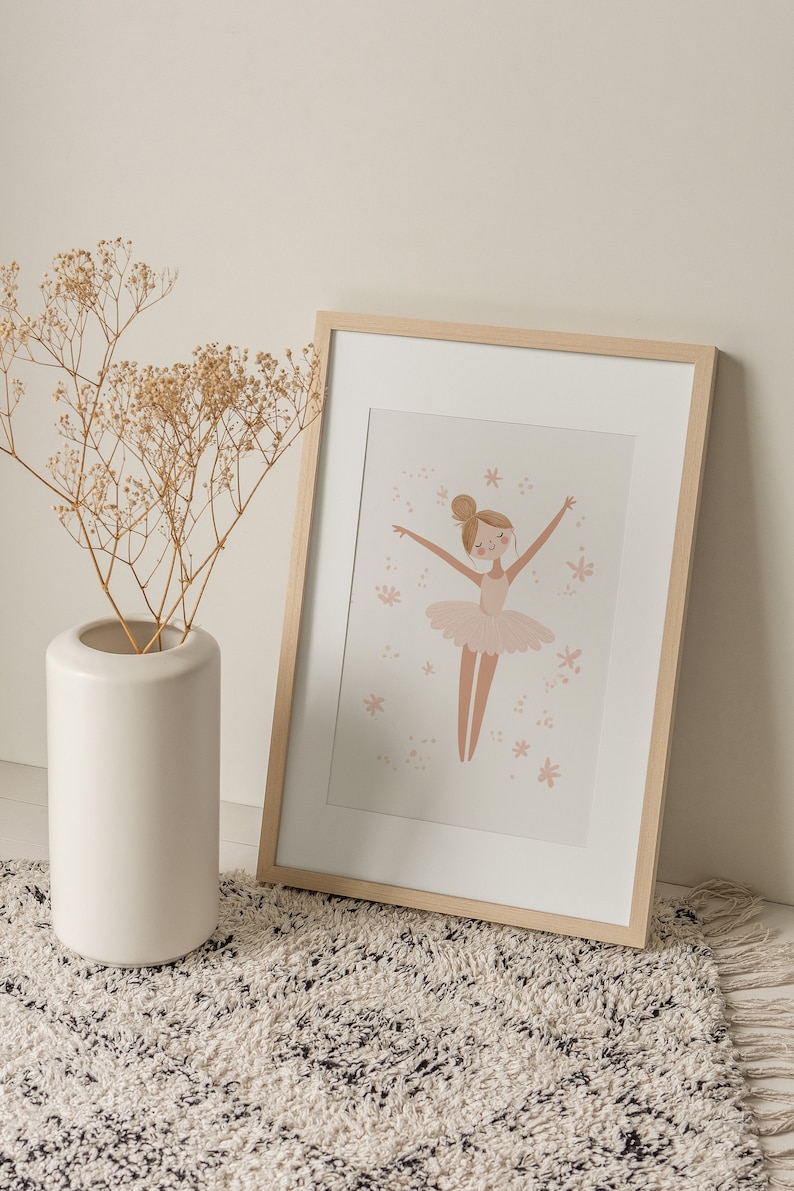 May include: A framed illustration of a ballerina in a pink tutu with a light pink background and small pink flowers. The frame is made of light wood.