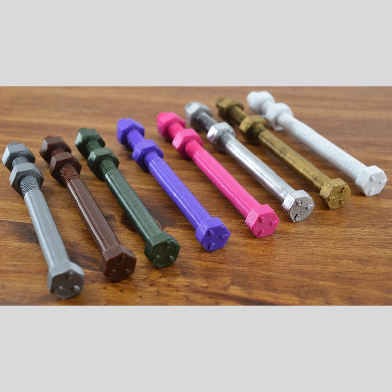May include: A set of eight colorful metal bolts with hexagonal heads. The bolts are arranged in a row from left to right, with the colors ranging from silver to gold. The bolts are all the same size and shape.