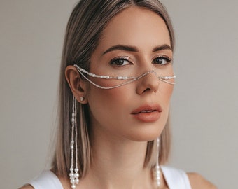 Puede incluir: Una mujer con cabello castaño claro lleva un top blanco sin mangas y una delicada pieza de nariz de perlas y cadena. La pieza de nariz tiene largos hilos de perlas que cuelgan de cada lado.