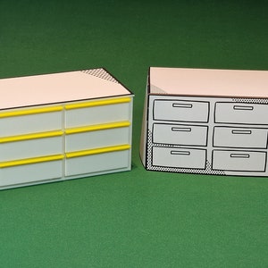 May include: Two white cardboard model cabinets with drawers. The cabinet on the left has six drawers with yellow trim. The cabinet on the right has six drawers and two doors.