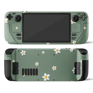 Peut inclure: Une console de jeu portable verte avec un motif de marguerites. La console a un écran noir, des boutons noirs et des joysticks noirs. La console est présentée de face et de dos.