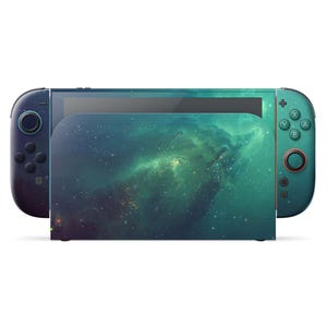 Puede incluir: Una consola Nintendo Switch con un diseño personalizado que presenta un patrón de nebulosa en tonos azules y verdes. Los mandos Joy-Con tienen un efecto degradado, pasando del azul oscuro al turquesa. La base también muestra el diseño de la nebulosa.