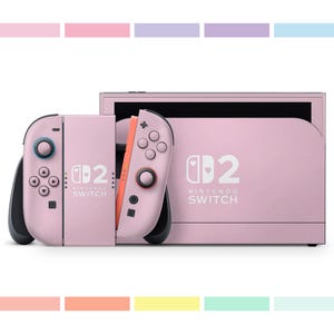 以下が含まれることがあります： ピンク色のNintendo Switchコンソールと、お揃いのJoy-Conコントローラー。コンソールにはNintendo Switchのロゴと白い数字の「2」が表示されています。Joy-Conコントローラーは黒いアクセントとオレンジ色のボタンが付いています。