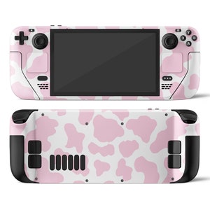 May include: A pink and white handheld gaming console with a cow print design. The console has a black screen, black buttons, and black joysticks.