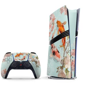 Puede incluir: Una consola PlayStation 5 de color azul claro y blanco con un diseño floral y peces koi. La consola tiene un diseño vertical y el mando tiene un diseño estándar.