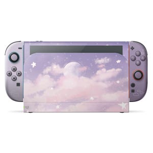 Könnte beinhalten: Eine lavendelfarbene Nintendo Switch-Konsole mit passenden Joy-Con-Controllern. Die Konsole hat ein verträumtes Design mit Vollmond, Wolken und Sternen. Die Controller haben einen lila Farbverlauf und die Knöpfe sind schwarz und rot.