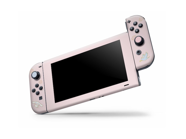 May include: A pink Nintendo Switch console with a custom design featuring a cartoon dog and a bird. The console is in handheld mode with the Joy-Con controllers attached.