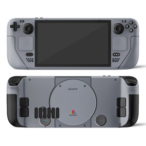 Puede incluir: Una consola de juegos portátil gris con un logotipo de PlayStation negro y el texto "PlayStation" en la parte delantera. La consola tiene un diseño gris y negro que se asemeja a la consola PlayStation original.