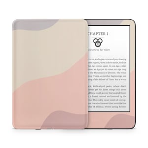 Puede incluir: Un lector electrónico Kindle Paperwhite rosa y beige con una portada de libro digital que presenta un título de capítulo y un símbolo. La portada es para una novela de fantasía titulada "The Flame of Tar Valon".