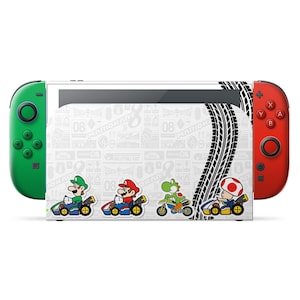Könnte beinhalten: Eine Nintendo Switch-Konsole mit grünen und roten Joy-Con-Controllern. Die Konsole hat ein weißes Design mit Mario Kart-Charakteren, die Rennen fahren, Reifenabdrücken und dem Text "MARIOKART".