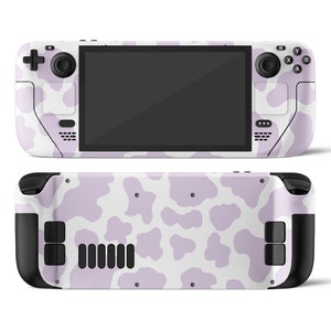 May include: A handheld gaming console with a white and purple cow print design. The console has a black screen and black buttons.