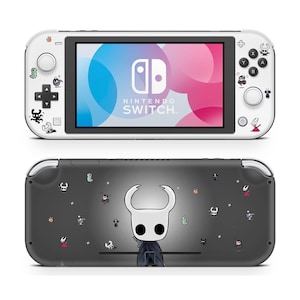 Puede incluir: Una consola Nintendo Switch Lite blanca con una pantalla colorida y pegatinas decorativas. La parte trasera de la consola es de color gris oscuro con una gran ilustración de personaje y pegatinas pequeñas adicionales.