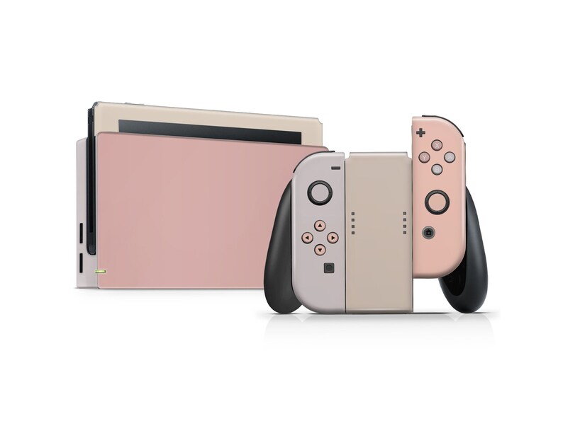 May include: A pink and beige Nintendo Switch console with two controllers. The console is in a closed position and the controllers are attached to the sides.
