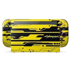 以下が含まれることがあります： 黄色と黒のサイバーパンク2077をテーマにしたNintendo Switchコンソール。ゲームのロゴが入った回路基板のデザインが特徴です。コントローラーとコンソールの本体は黄色で、黒のアクセントが付いています。