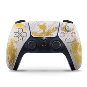 Peut inclure: Manette PlayStation 5 blanche et noire avec un motif de coups de pinceau dor&eacute;s et une illustration de personnage. La manette pr&eacute;sente le logo PlayStation et la disposition standard des boutons.