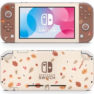 以下が含まれることがあります： 秋をテーマにした茶色とベージュの模様が施された、ベージュのニンテンドースイッチライト。背面には、葉、どんぐり、キノコの模様が描かれている。前面は、青とピンクのグラデーションの背景に、ニンテンドースイッチのロゴが描かれている。