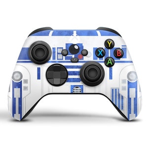 K&ouml;nnte beinhalten: Ein wei&szlig;er und blauer Xbox-Controller mit einem Star Wars R2-D2-Design. Der Controller hat schwarze Tasten und ein schwarzes Steuerkreuz.
