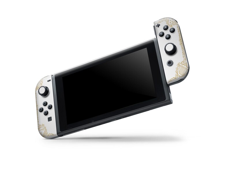 May include: A white Nintendo Switch console with gold accents and a matching Joy-Con controller. The console is in handheld mode with the screen displaying a black screen.