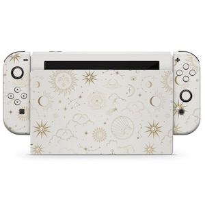 Pode incluir: Console Nintendo Switch branca com uma capa personalizada que apresenta um padrão celestial de luas, estrelas e sóis dourados sobre um fundo branco.