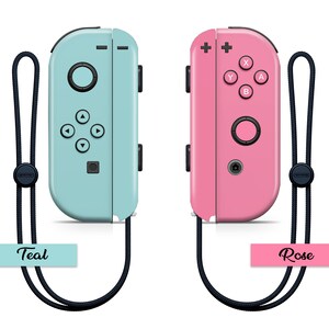 K&ouml;nnte beinhalten: Zwei Nintendo Switch Joy-Con-Controller, einer in T&uuml;rkis und einer in Rosa, mit schwarzen Handgelenksb&auml;ndern. Der t&uuml;rkisfarbene Controller hat die Worte "Teal" darunter gedruckt. Der rosafarbene Controller hat die Worte "Rose" darunter gedruckt.