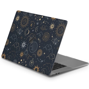 Könnte beinhalten: Ein Laptop mit einem dunkelblauen und goldenen Himmelsdesign auf dem Deckel. Das Design zeigt Sterne, Monde und Sonnen.