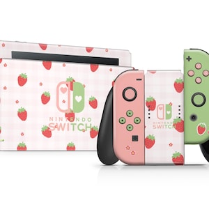 以下が含まれることがあります： イチゴとギンガムチェック柄のピンクとグリーンのNintendo Switch本体とJoy-Conコントローラー。本体には「NINTENDO SWITCH」の文字が印刷されています。