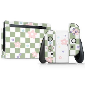 以下が含まれることがあります： 花柄デザインのNintendo Switch本体とコントローラー。本体とコントローラーは、ピンク、紫、青の花のアクセントが付いた、緑と白のチェック柄で覆われています。コントローラーは黒色です。
