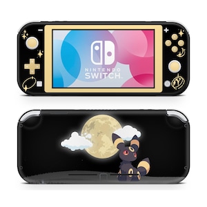 Könnte beinhalten: Schwarze Nintendo Switch Lite Konsole mit goldenen Akzenten und einem farbenfrohen Bildschirm. Auf der Vorderseite befindet sich das Nintendo Switch-Logo. Die Rückseite zeigt ein Design mit Vollmond, Wolken und einem Umbreon-Charakter.