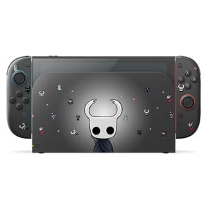 Può includere: Console Nintendo Switch nera con un design personalizzato raffigurante un personaggio bianco con testa a forma di mezzaluna e mantello scuro. Il design è sulla dock station e sui controller Joy-Con.