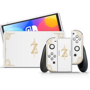Può includere: Console Nintendo Switch bianca e controller Joy-Con con una skin personalizzata che presenta un logo Zelda dorato e un bordo decorativo.