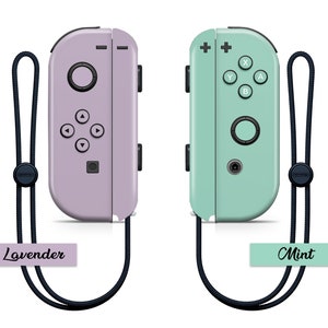 K&ouml;nnte beinhalten: Zwei Nintendo Switch Joy-Con-Controller, einer in Lavendel und einer in Mintgr&uuml;n, mit schwarzen Handgelenksb&auml;ndern. Die Controller sind nebeneinander mit den Etiketten "Lavender" und "Mint" darunter abgebildet.