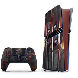 May include: A black and red video game console featuring a graphic of a superhero's face. The console is next to a black video game controller with a similar design.