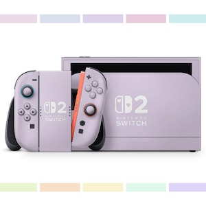 以下が含まれることがあります： ラベンダー色のNintendo Switch本体と、お揃いのJoy-Conコントローラー。コントローラーは黒のアクセントとオレンジ色のディテールが特徴です。本体とコントローラーには、Nintendo Switchのロゴと数字の「2」が表示されています。