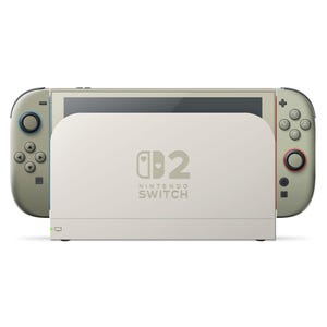 Może przedstawiać: Konsola Nintendo Switch w kremowo-oliwkowej kolorystyce, zadokowana w białej stacji ładującej. Stacja posiada logo Nintendo Switch i małą zieloną lampkę. Kontrolery Joy-Con są oliwkowe z niebieskimi i czerwonymi akcentami.