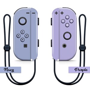 K&ouml;nnte beinhalten: Zwei Nintendo Switch Joy-Con-Controller, einer in Marineblau und einer in Lila, mit schwarzen Handgelenkschlaufen. Die Controller sind nebeneinander mit den Kn&ouml;pfen zum Betrachter hin angeordnet. Die Schlaufen haben Etiketten mit der Aufschrift "Navy" und "Purple".