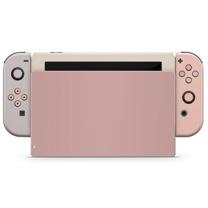 May include: A pink and beige Nintendo Switch console with detachable controllers. The console is closed and the screen is off.