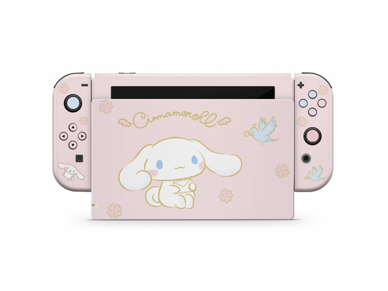 May include: Pink Nintendo Switch console with a Cinnamoroll character design. The console features a white dog with blue eyes and a pink nose, surrounded by pink flowers and a blue bird.