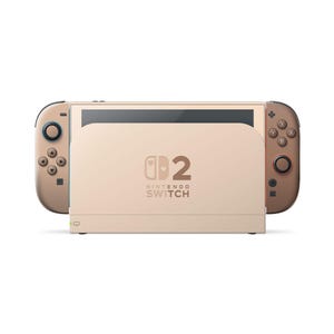 Puede incluir: Una consola de videojuegos Nintendo Switch 2 de color beige con una base central que muestra el texto Nintendo Switch 2 e iconos de corazones. El dispositivo incluye dos mandos desmontables a los lados con joysticks oscuros y botones.