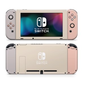 May include: A pale pink and beige Nintendo Switch console with a white Nintendo Switch logo and the text "NINTENDO SWITCH" on the front. The console is in a closed position.